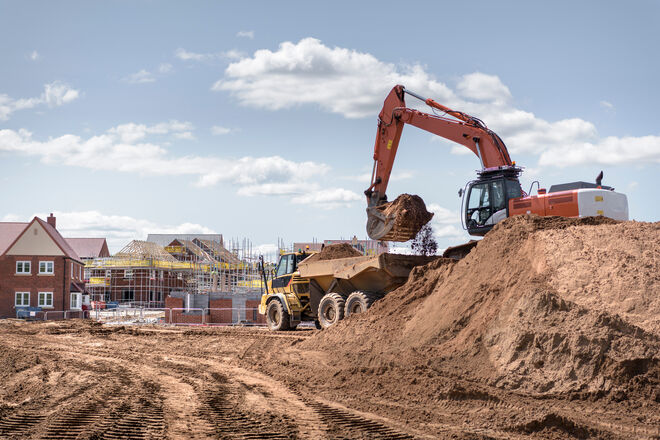 Houses under construction with machinery in foreground. 